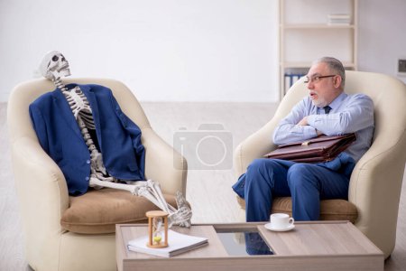 Foto de Viejo jefe y esqueleto masculino en concepto de reunión de negocios - Imagen libre de derechos