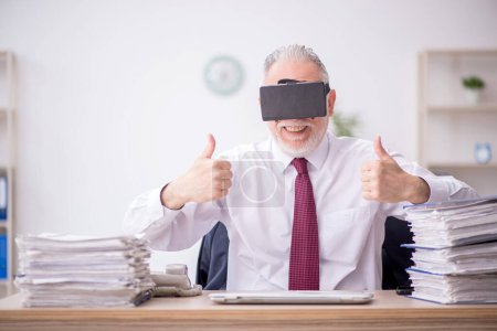 Photo for Old employee wearing virtual glasses at workplace - Royalty Free Image