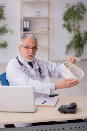 Photo for Old doctor holding neck brace in the clinic - Royalty Free Image