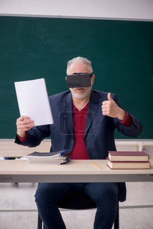 Foto de Old teacher wearing virtual glasses in the classroom - Imagen libre de derechos