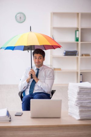Téléchargez les photos : Young employee holding an umbrella at workplace - en image libre de droit