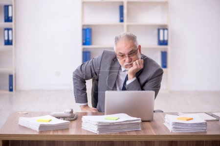 Photo for Old businessman employee unhappy with excessive work at workplace - Royalty Free Image
