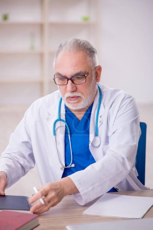 Téléchargez les photos : Old doctor sitting at the hospital - en image libre de droit
