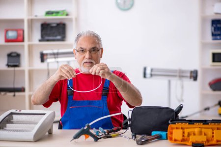 Foto de Viejo reparador masculino reparando calentador en el taller - Imagen libre de derechos