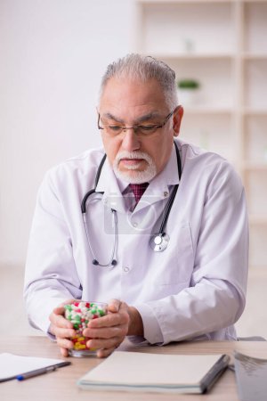 Photo for Old doctor suggesting pills in the clinic - Royalty Free Image