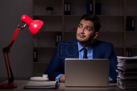 Photo for Young employee working late at workplace - Royalty Free Image