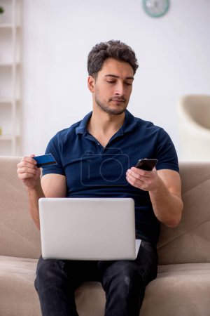 Photo for Young man holding credit card at home - Royalty Free Image