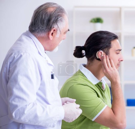 Foto de Paciente masculino con problemas auditivos que visita al médico otorrinolaringólogo - Imagen libre de derechos