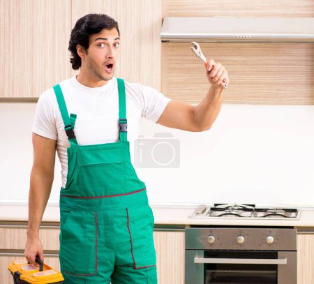 Photo for The young contractor repairing oven in kitchen - Royalty Free Image