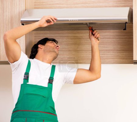 Téléchargez les photos : Le jeune entrepreneur réparer climatiseur dans la cuisine - en image libre de droit