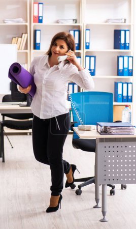 Téléchargez les photos : L'employée d'âge moyen faisant des exercices au bureau - en image libre de droit