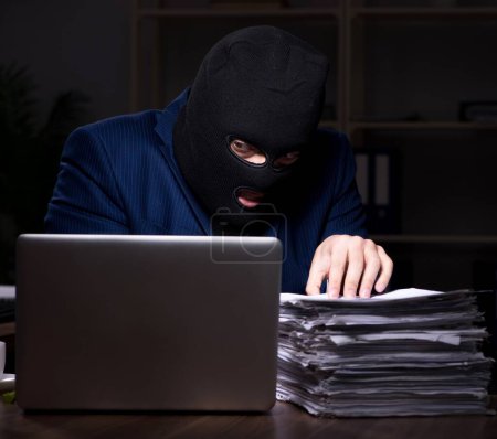 Foto de El empleado masculino robando información en la oficina por la noche - Imagen libre de derechos