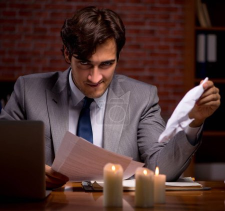 Téléchargez les photos : L'homme d'affaires travaillant tard dans le bureau avec de la lumière de bougie - en image libre de droit
