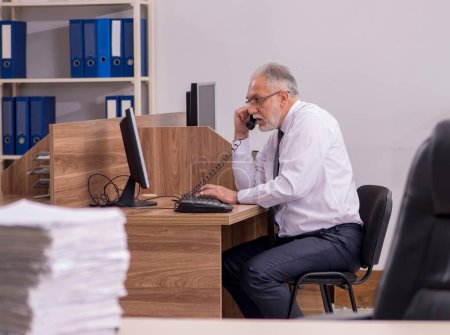 Téléchargez les photos : Vieil employé mécontent du travail excessif au bureau - en image libre de droit