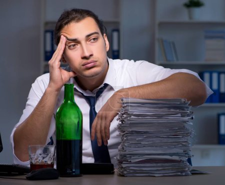 Téléchargez les photos : Homme d'affaires accro à l'alcool travaillant tard - en image libre de droit