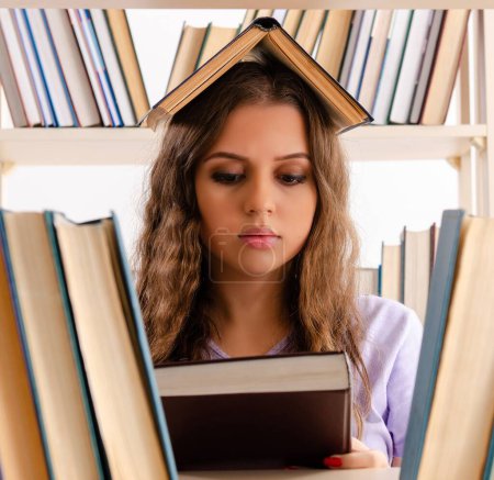 Foto de La joven estudiante preparándose para los exámenes en la biblioteca - Imagen libre de derechos