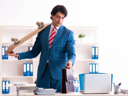 Foto de El joven hombre de negocios guapo con longboard en la oficina - Imagen libre de derechos