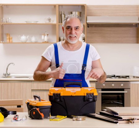 Photo for The aged contractor repairman working in the kitchen - Royalty Free Image