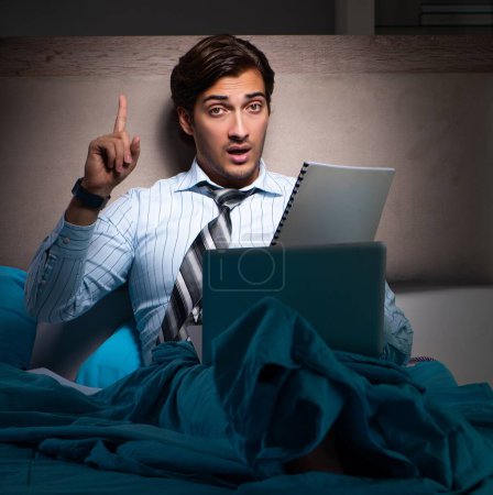 Foto de El hombre de negocios cansado que trabaja horas extras en casa por la noche - Imagen libre de derechos