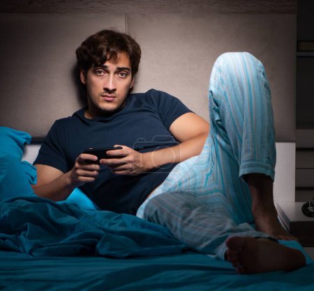 Foto de El joven mandando mensajes de texto en el móvil tarde en la noche - Imagen libre de derechos