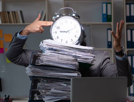 Téléchargez les photos : Le jeune employé masculin travaillant tard au bureau - en image libre de droit