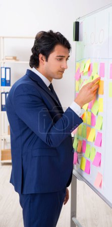 Photo for The young handsome employee in front of whiteboard with to-do list - Royalty Free Image