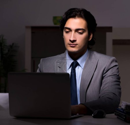 Foto de El joven empleado guapo y demasiado trabajo en la oficina - Imagen libre de derechos