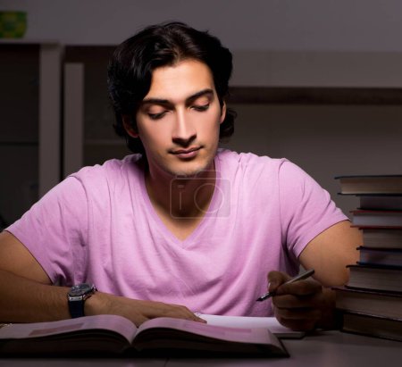 Téléchargez les photos : L'étudiant beau mâle se prépare pour les examens tard à la maison - en image libre de droit