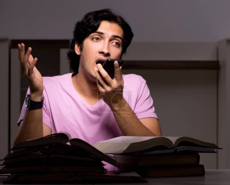 Téléchargez les photos : L'étudiant beau mâle se prépare pour les examens tard à la maison - en image libre de droit