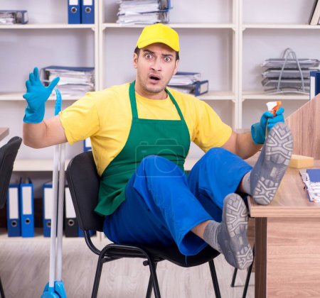 Photo for The young male contractor cleaning the office - Royalty Free Image