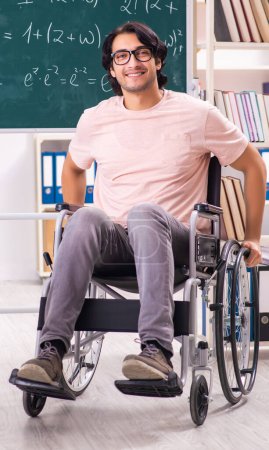 Téléchargez les photos : Le jeune bel homme en fauteuil roulant devant le tableau - en image libre de droit