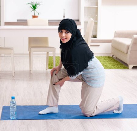 Téléchargez les photos : La jeune femme en hijab faisant des exercices à la maison - en image libre de droit