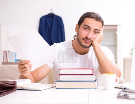 Foto de El joven estudiante masculino preparándose para los exámenes en casa - Imagen libre de derechos