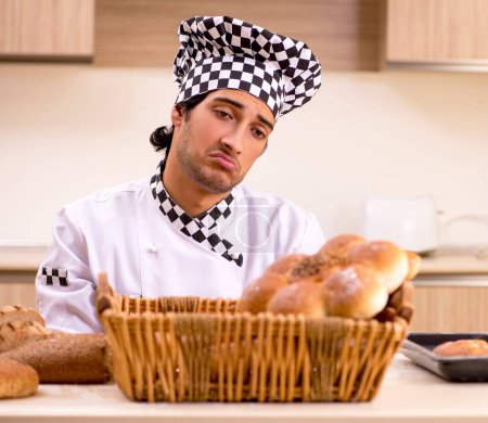 Téléchargez les photos : Le jeune boulanger masculin travaillant dans la cuisine - en image libre de droit