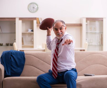 Photo for Senior male boss employee throwing rugby ball at home - Royalty Free Image