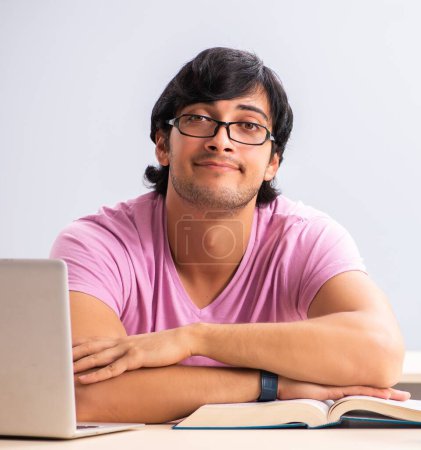 Téléchargez les photos : Le jeune étudiant mâle assis dans la classe - en image libre de droit