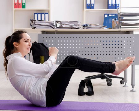 Téléchargez les photos : The female employee doing sport exercises in the office - en image libre de droit