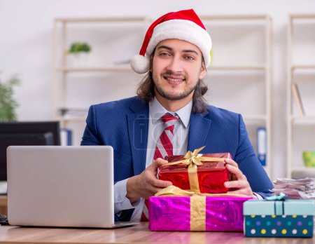 Téléchargez les photos : Jeune employé travaillant au bureau à la veille de Noël - en image libre de droit