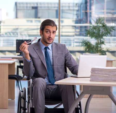Téléchargez les photos : Jeune employé en fauteuil roulant travaillant au bureau - en image libre de droit