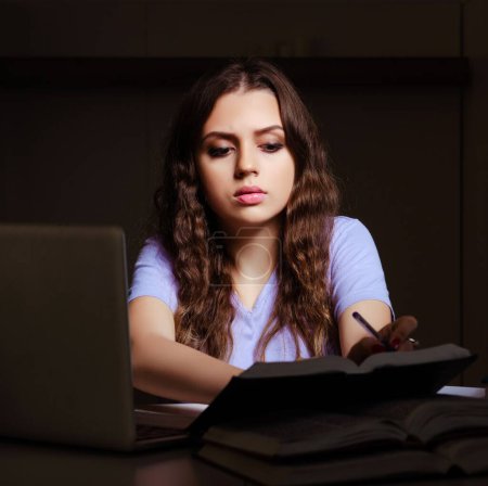 Foto de La joven estudiante preparándose para los exámenes tarde en casa - Imagen libre de derechos