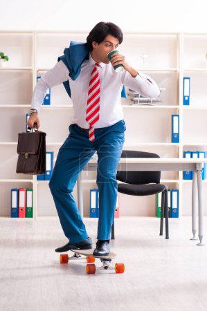 Photo for The young handsome businessman with longboard in the office - Royalty Free Image