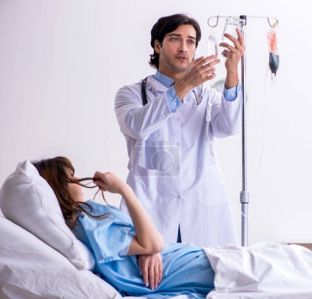 Foto de El médico masculino visitando a la paciente femenina en la sala - Imagen libre de derechos