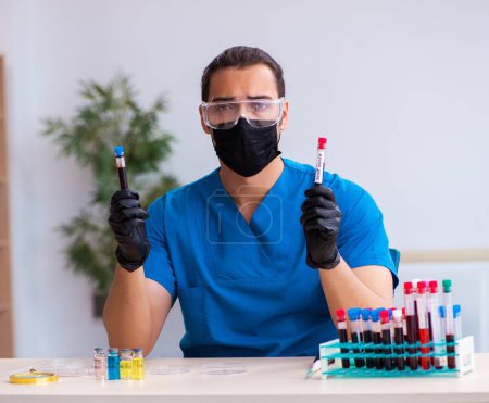 Foto de Bioquímico masculino analizando muestras de sangre en concepto pandémico - Imagen libre de derechos