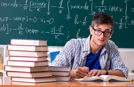 Téléchargez les photos : Le jeune étudiant masculin qui étudie les mathématiques à l'école - en image libre de droit