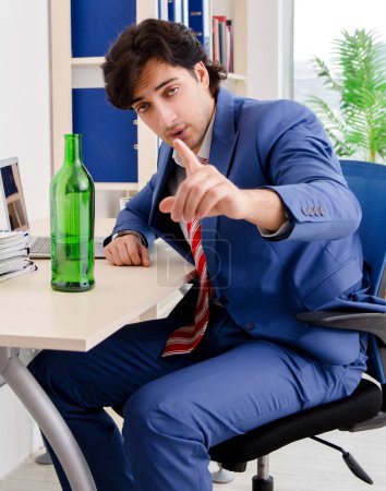 Foto de The young businessman employee drinking in the office - Imagen libre de derechos