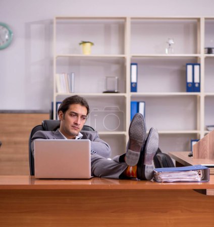 Photo for Young employee sleeping at workplace - Royalty Free Image