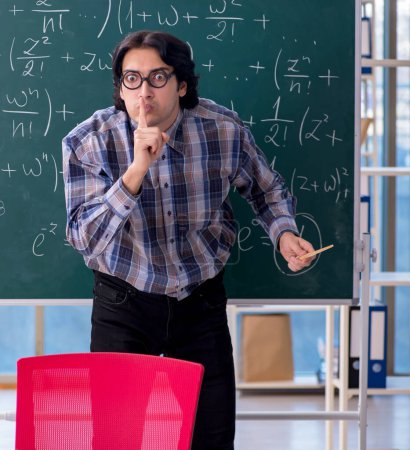 Foto de El joven profesor divertido de matemáticas frente a la pizarra - Imagen libre de derechos
