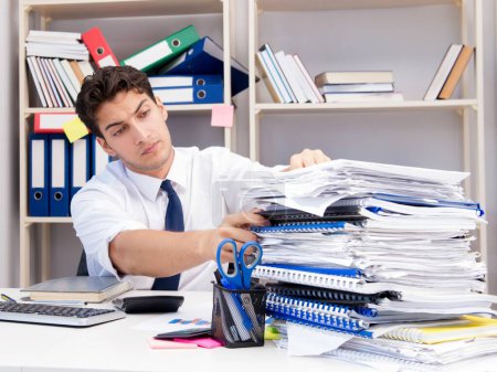 Photo for Businessman working in the office with piles of books and papers doing paperwork - Royalty Free Image