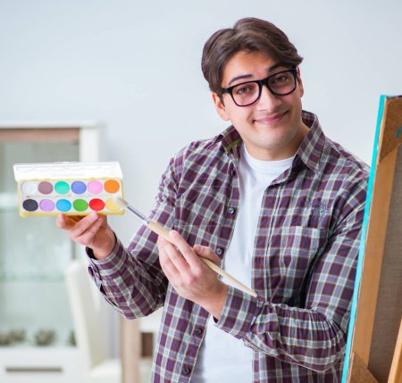 Téléchargez les photos : Le jeune artiste masculin dessine des images dans un studio lumineux - en image libre de droit