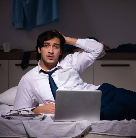 Foto de El joven empleado que trabaja en casa después del turno de noche - Imagen libre de derechos